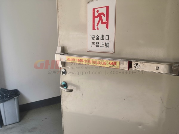 逃生门锁警示标识，与铮亮的不锈钢锁体形成强烈对比